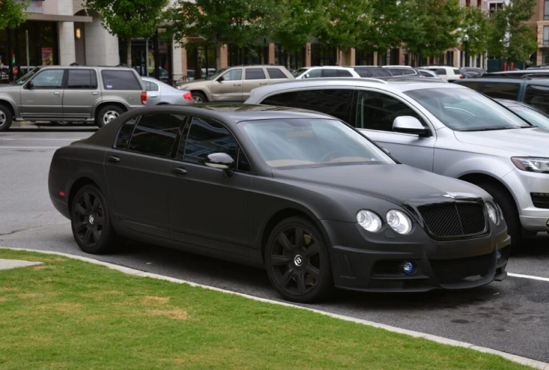 Matte black luxury sedan parked on street.