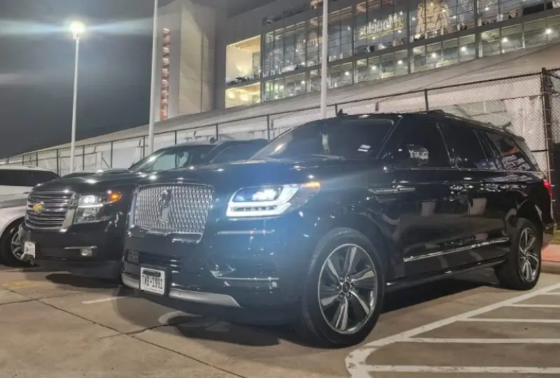Luxury SUVs parked near a building at night.