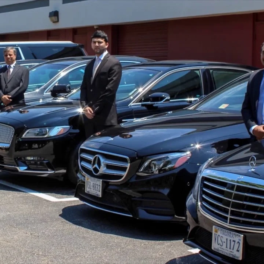 Men in suits standing by luxury cars.